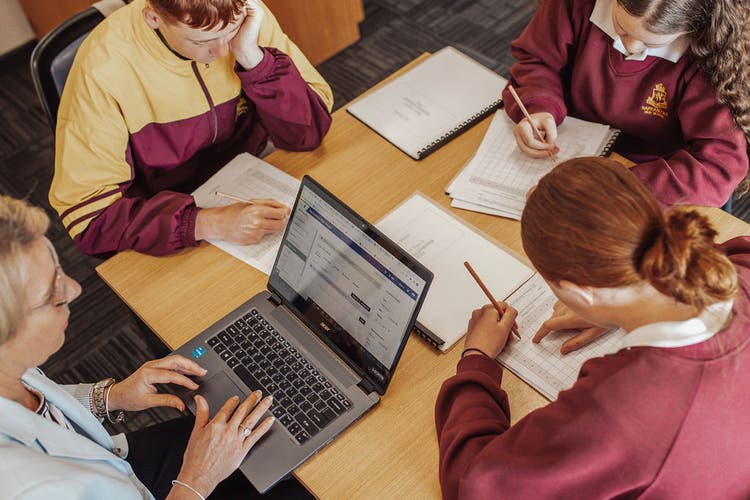 Students sitting at a desk with a teacher